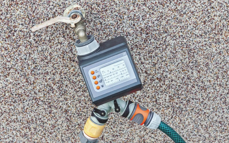 Outdoor garden hose spigot with a hose-thread adapter and irrigation timer attached, the starting point for connecting a drip system
