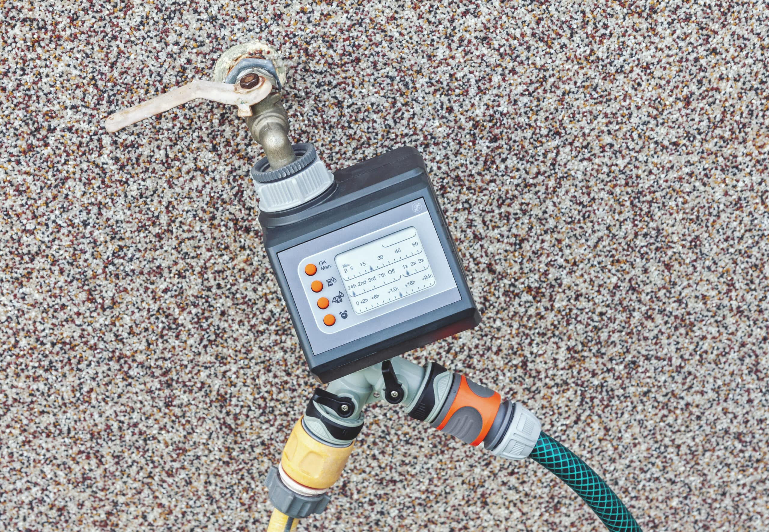 Robinet de tuyau d'arrosage extérieur avec un adaptateur de filetage et un programmateur d'irrigation fixés, le point de départ pour connecter un système goutte à goutte