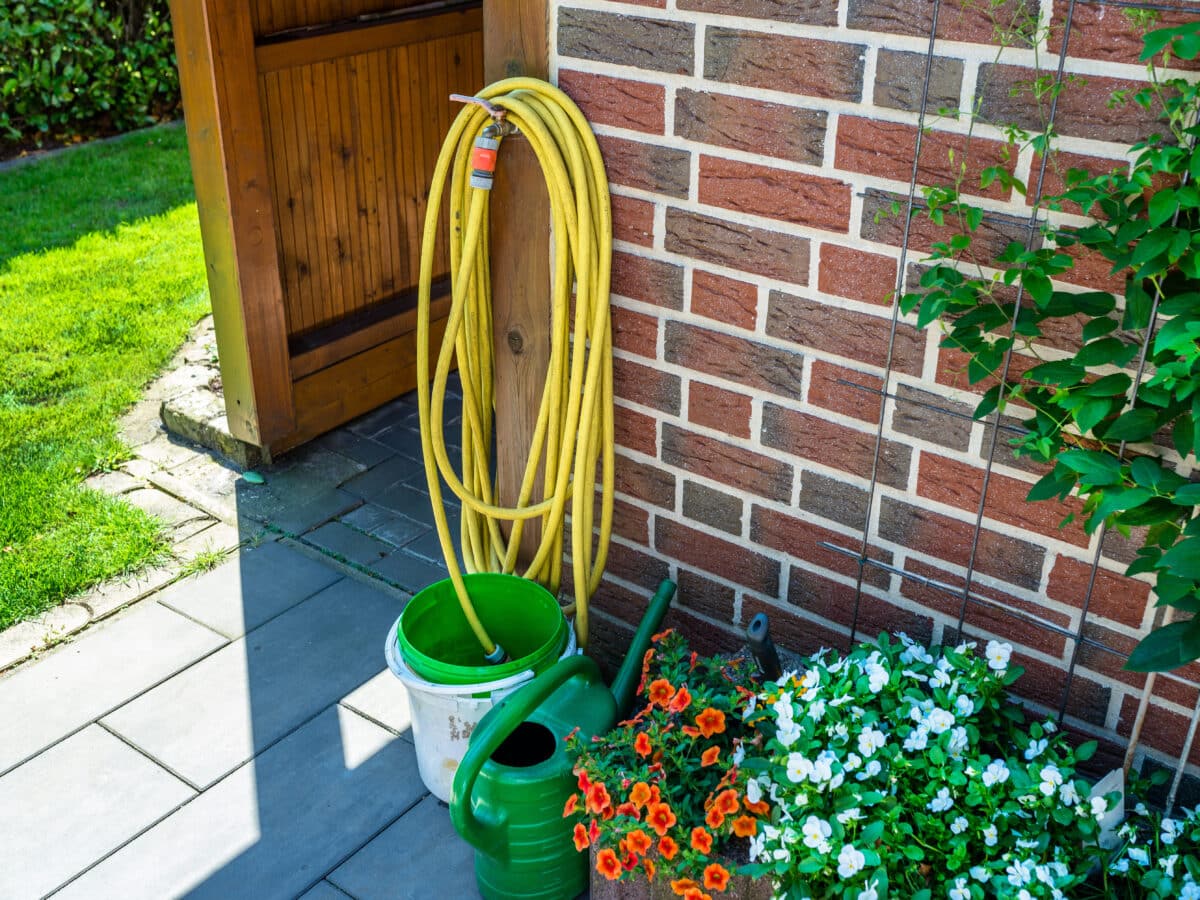 Soaker hose laid in a shallow trench parallel to a house foundation