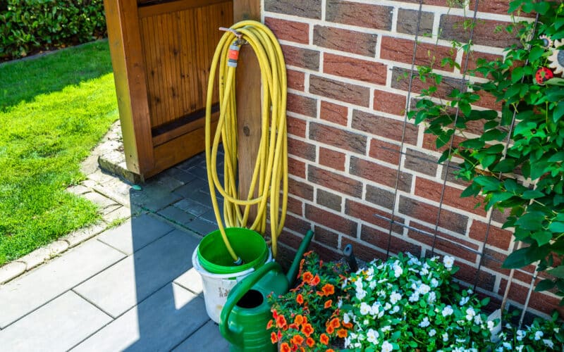 Soaker hose laid in a shallow trench parallel to a house foundation