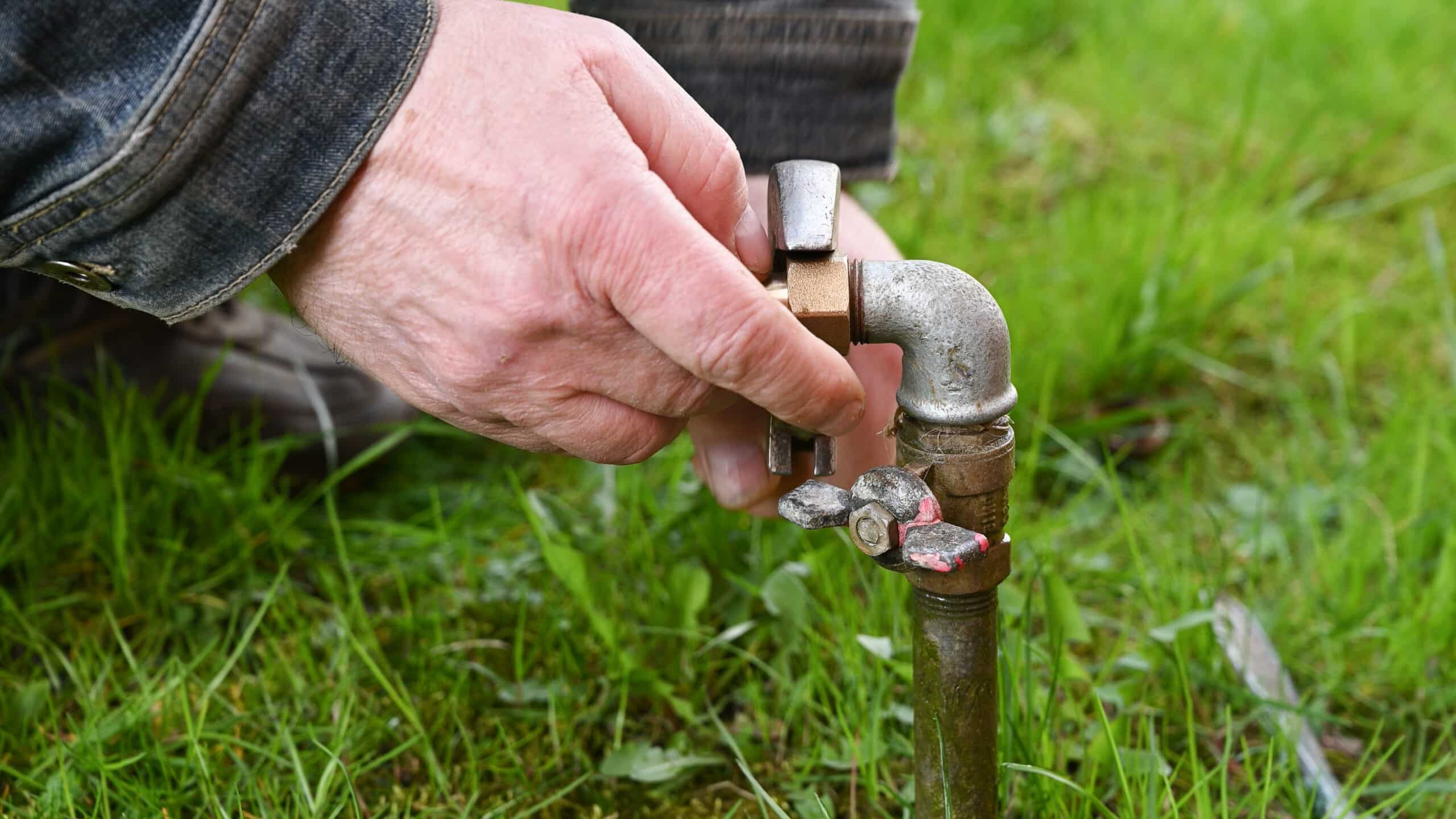Gros plan de mains travaillant sur un raccord de tuyau d'irrigation de jardin lors d'un entretien de routine