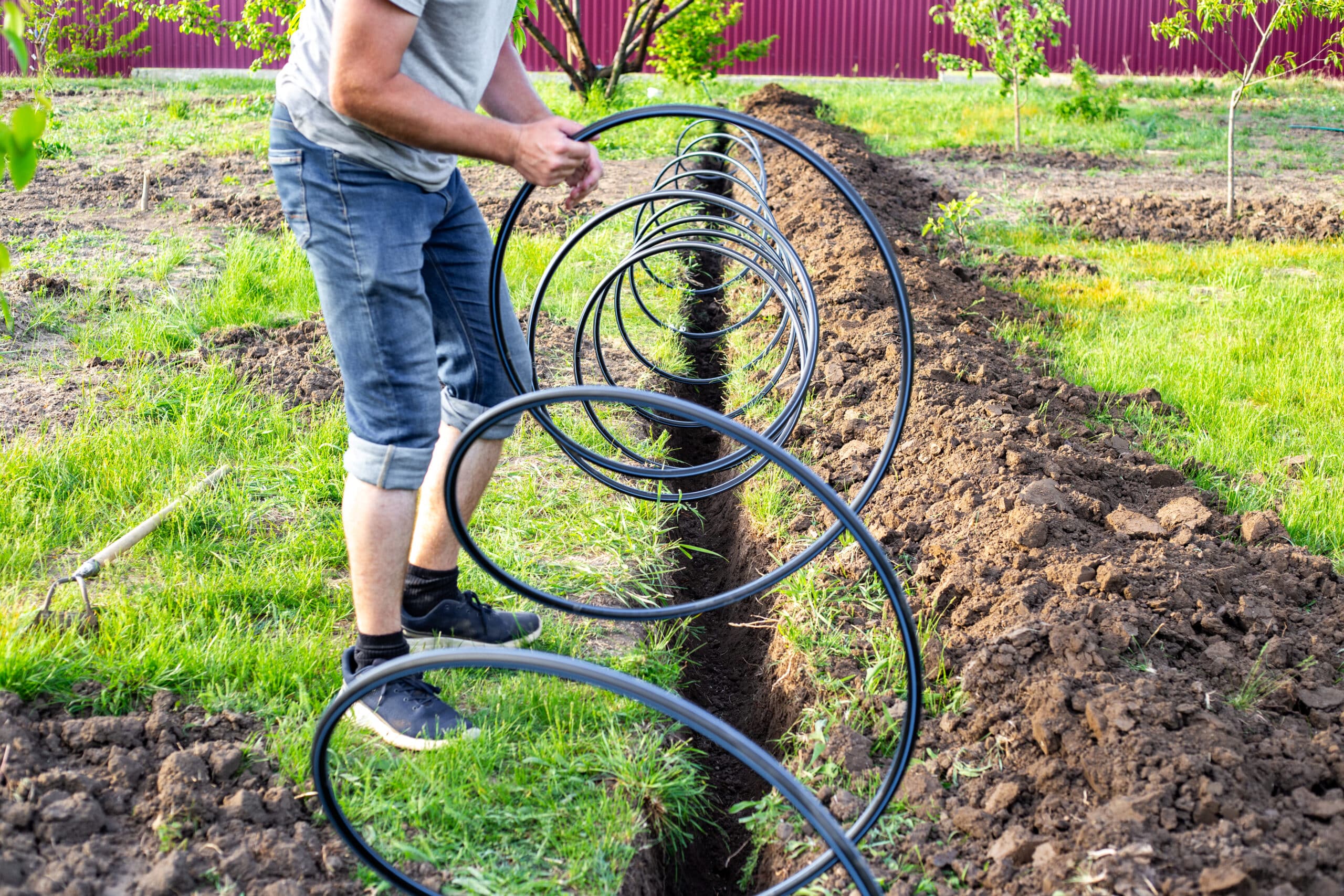 Tuyau d'irrigation goutte à goutte enterré posé dans une tranchée creusée en travers d'une pelouse pendant l'installation