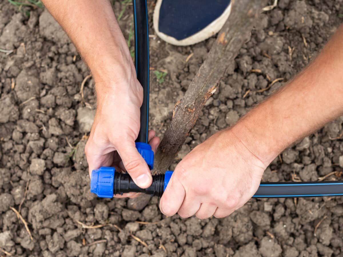 A gardener installing a drip irrigation system kit by connecting HDPE tubing fittings